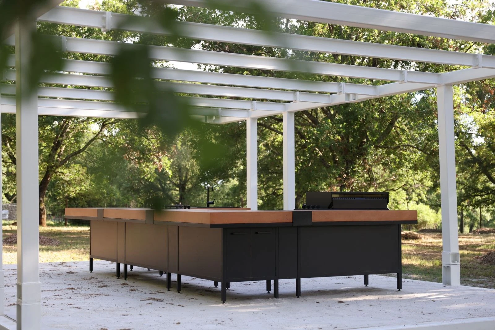 ForaFuoco terracotta and black outdoor kitchen under a white pergola